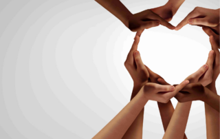 A group of students hands and arms clasp together in support to make the outline of a heart